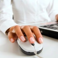 Woman’s hands touching computer mouse and keys of black opened laptop